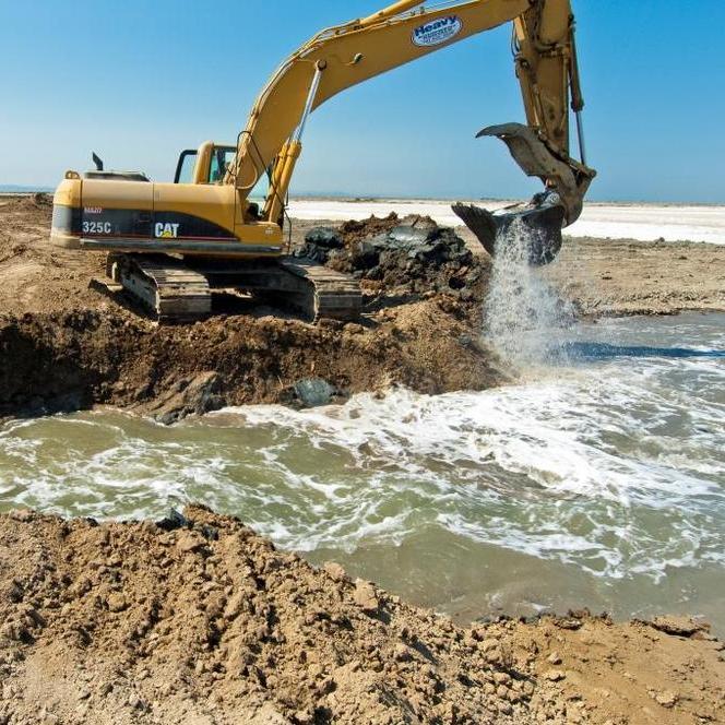 An excavator chews open a levee to connect Eden Landing ponds to Bay tides. Credit: Judy Irving, Pelican Media.
