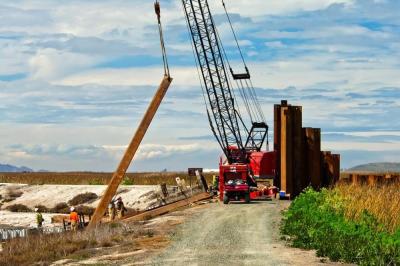 Workers and a crane putting in sheet pilings for a water control structure at Pond A16 to control water for shorebirds. Credit: Judy Irving, Pelican Media.