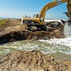 An excavator chews open a levee to connect Eden Landing ponds to Bay tides. Credit: Judy Irving, Pelican Media.