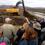 The crowd snaps photos as the excavator digs away to open Alviso Pond A17 to Bay tides. Credit: Judy Irving, Pelican Media.