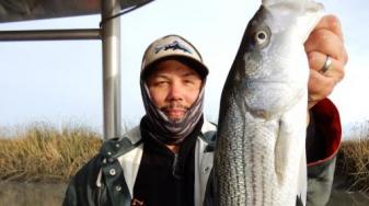 Levi Lewis with striped bass. Credit: James Ervin