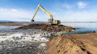 Bay waters pour into a 300-acre Ravenswood pond as an earthmover digs open the levee. Credit: Charles Anderson